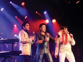 An Image of three Elvis Presleys on stage dressed in costumes from different eras.