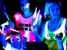 Two women and their young son, all wearing iridescent outfits and holding glowsticks