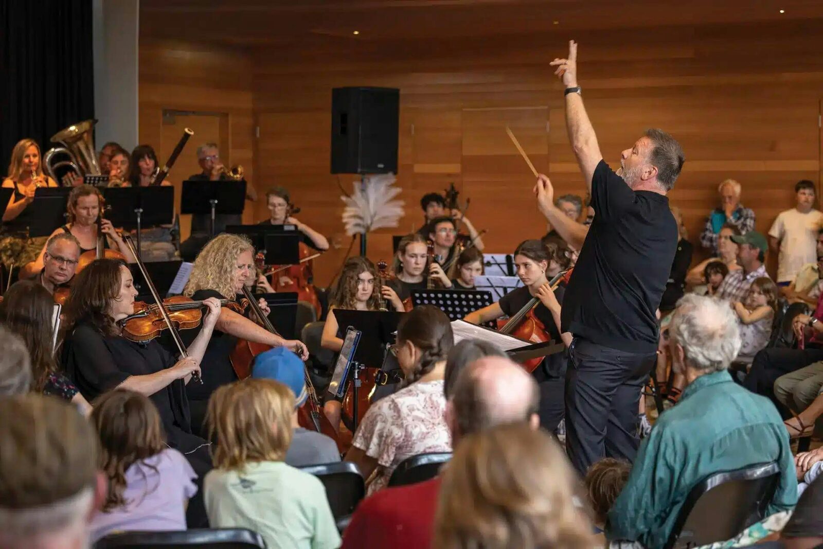 An audience watching a youth orchestra with a conductor in motion