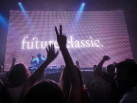 A DJ performing on stage in front of a large LED screen displaying the words âfuture classic.