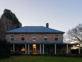 Dusk sets over a historic double-storey brick building. Two lights are on inside.