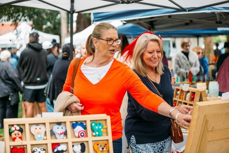 Two women looking at goods at an outdoor stall.