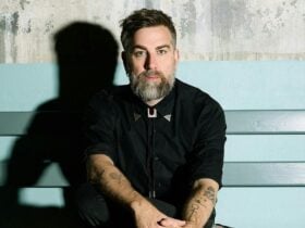 One male with a beard and wearing a black shirt, sitting on a bench.