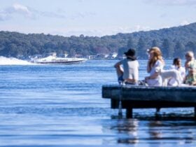 People sitting on a jetty looking at a boat for the Fast and Loud Festival