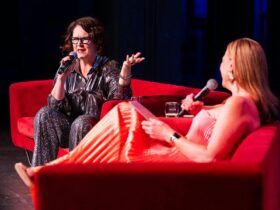 Annabel Crabb and Leigh Sales sitting on couches on stage and holding microphones