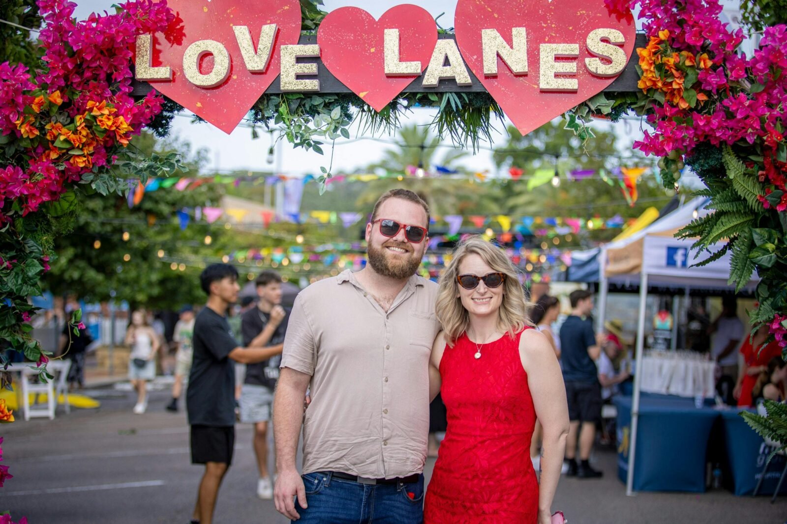 Man and woman pose for photo underneath a sign that says Love Lanes