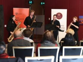 4 musicians holding instruments play before an audience