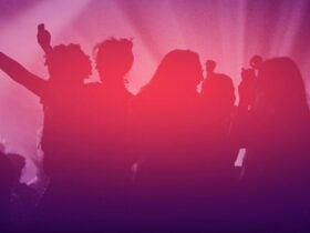 Silhouettes of people dancing and celebrating under pink and purple lights in a party