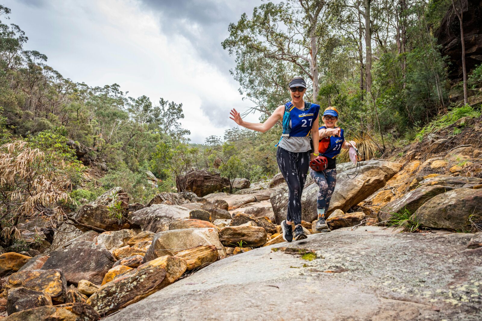 Two runners smiling pointing at the camera as they race through the Glenbrook Gorge.