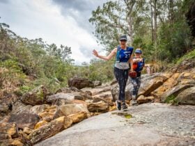 Two runners smiling pointing at the camera as they race through the Glenbrook Gorge.