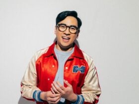 asian man with glasses wearing a red and beige jacket