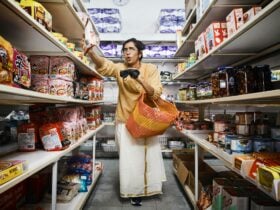 A Young Person stands in a supermarket aisle, reaching out to an item.