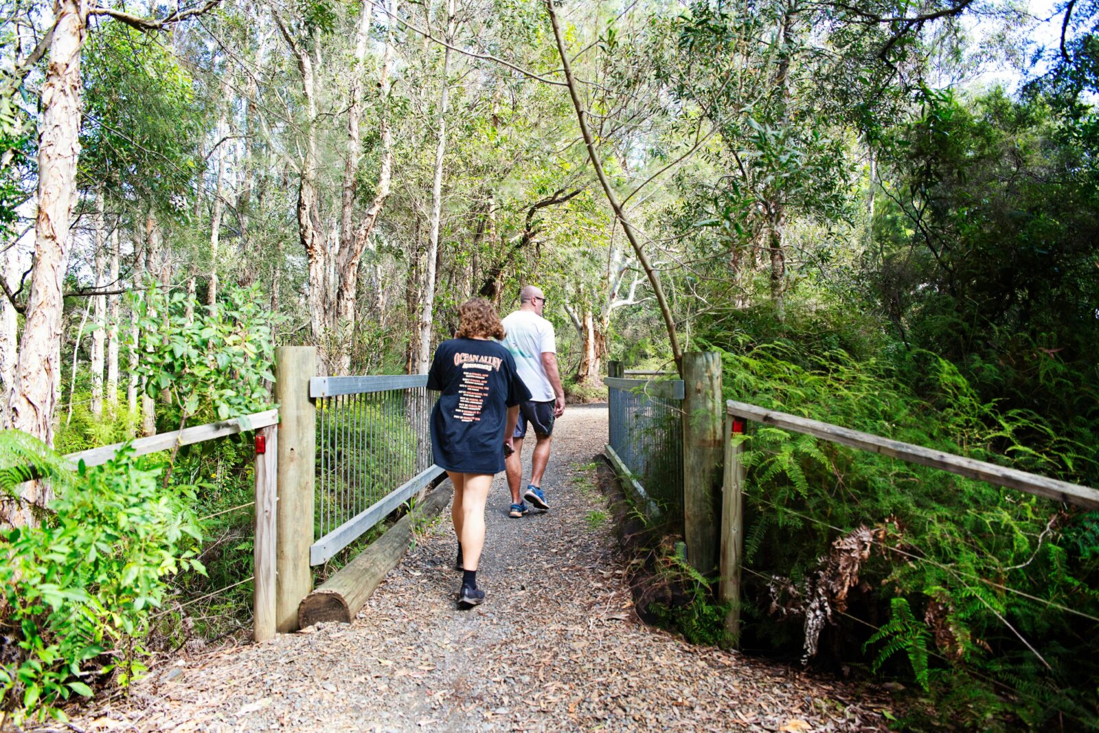 a man and woman walking along a bush track