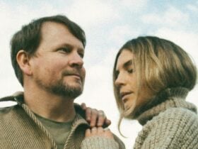 A close-up photo of a man and a woman standing outdoors under a cloudy blue sky.