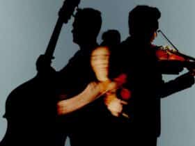 A violinist in the centre-front, a bassist to her left, and a violist to her right