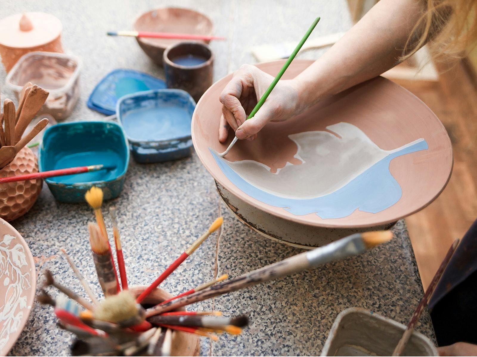 A student painting a pottery plate