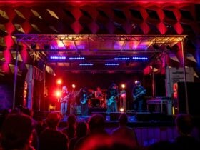 A band performs on a vibrant, colourful stage under dynamic red and blue lights at Parramatta Lanes.