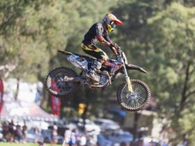 An MX1 Rider jumps as a crowd watches in the background