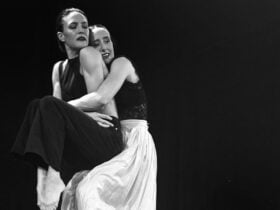 one dancer lifts another dancer in an embrace