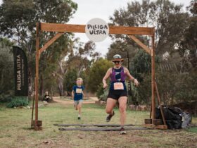 Two runners run through a timber finish arch with a 
