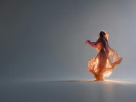 A female figure lit from behind in a warm orange glow, covered in a full veil