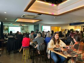 People enjoying chatting in a full pub. A screen is in the background.