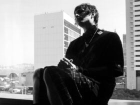 A person sits in silhouette by a large window, their features and dark clothing highlighted