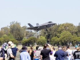 Air show patrons watch as an F-35A Lightning-2 fighter jet lifts off from the runway