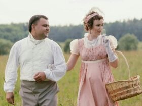 Couple dressed in regency outfits walk toward the camera