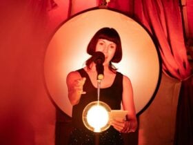 Megan Drury performing in an illuminated space with red drapes