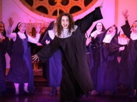 Deloris and fellow nuns singing and dancing in a church under purple lights.