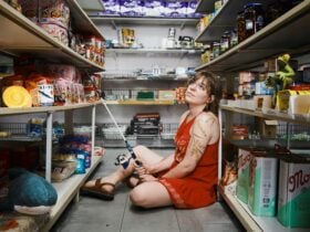 A Young Person, Jasmine Jenkins, sits in a supermarket aisle with a fishing rod.