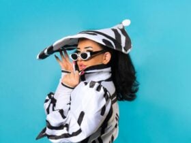 A woman with long hair, wearing stripes and a fun hat looking over her shoulder