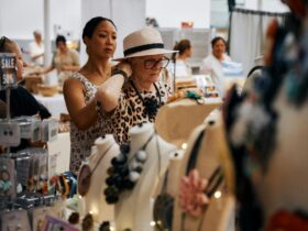 Stallholder helps a customer try on one of her artisan creations