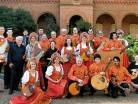 Members of the orchestra posing together in front of a building, some holding instruments