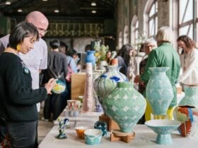 Two visitors look at colourful ceramic pieces on display on a table at Carriageworks
