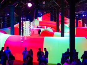 Indoor art installation of large inflatable snake shape in bright yellow and orange