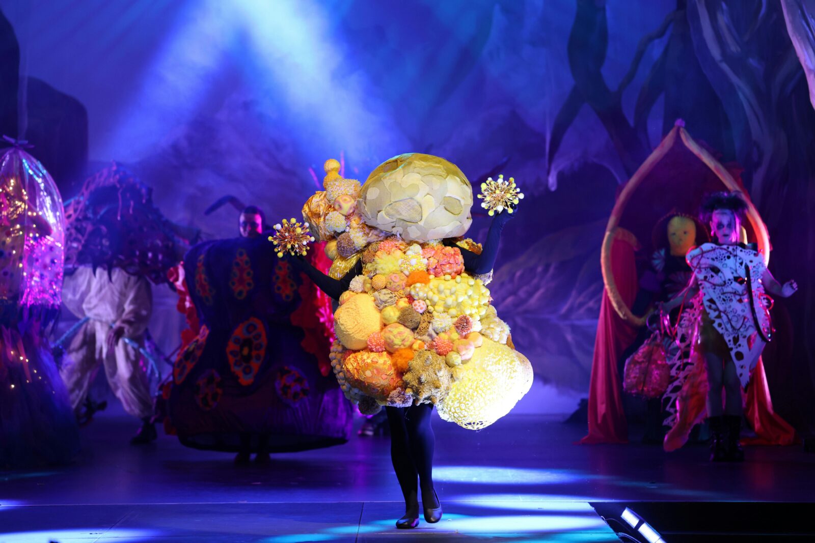 A yellow wearable art piece that encompasses the full body in spikey round forms.