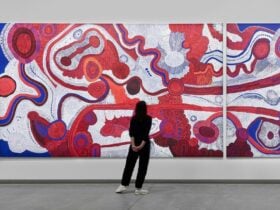 Visitor stands in front of one of Betty Pumani Kuntiwa's large scale paintings