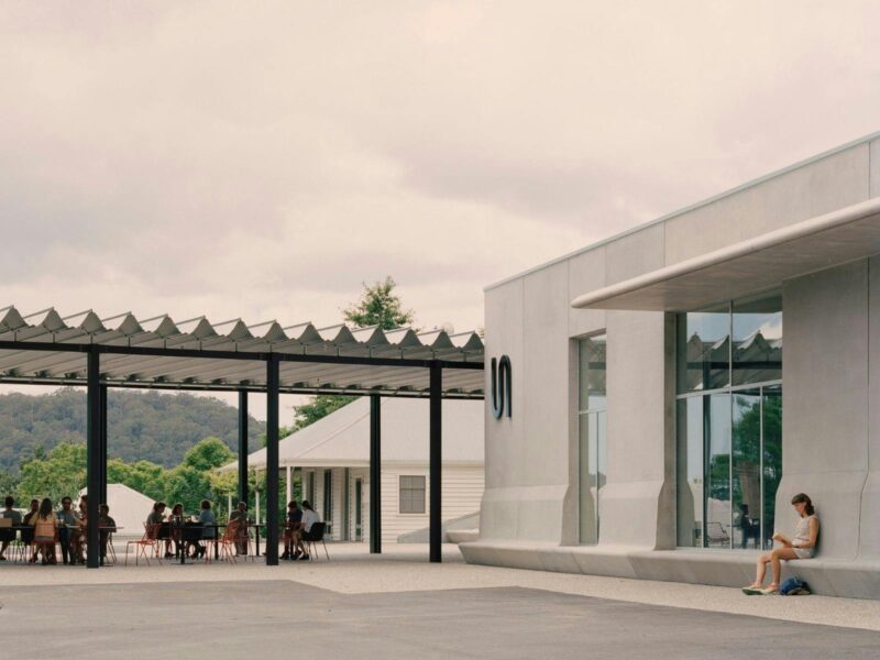 The concrete facade of the Art Museum and visitors enjoying their meals at the Ramox Cafe terrace
