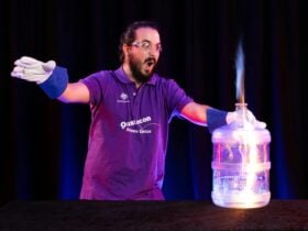 Questacon presenter holds a water cooler bottle with flames shooting out from inside.