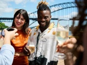 Woman in orange dress and man in white and yellow shirt drinking champagne