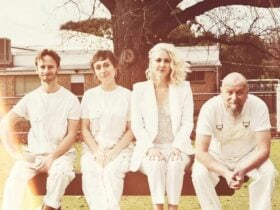 the audreys. Four people in white clothes sitting on a bench