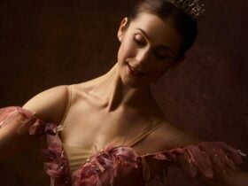 A dancer in a pink tutu looking down at the camera