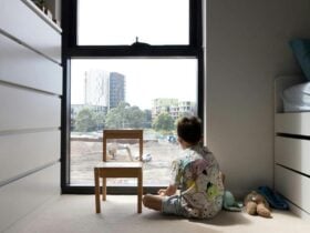 Young child looking outside the window of an apartment at construction site
