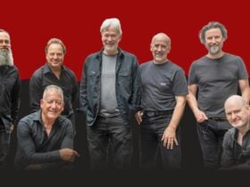 seven men dressed in dark colours in various poses on a red and black background