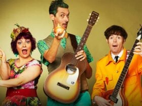 A kids band with 3 band members holding guitars and maracas, pulling silly faces