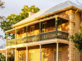 Double storey historic building faces the sunset. A golden glow is cast upon the facade