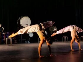 Two acrobatic dancers on their hands dancing in front of Taiko drums