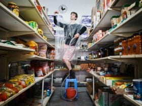 A Young Person, Joshua Di Mattina-Beven, stands on a chair in a supermarket with a water pipe.